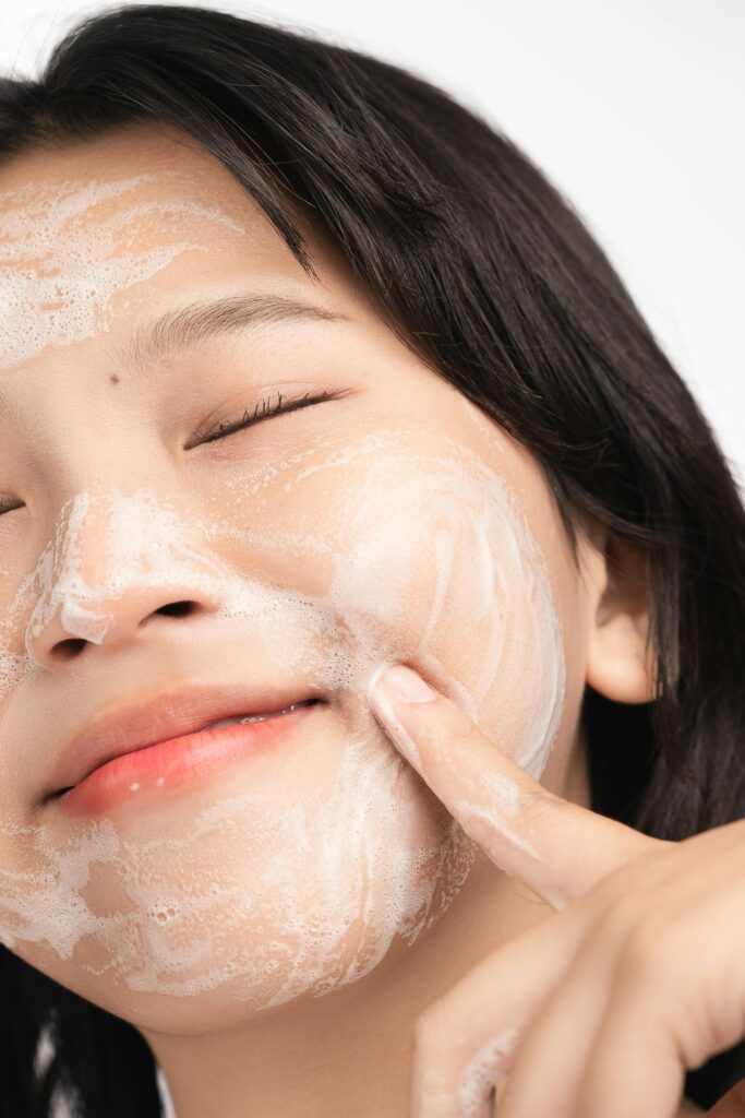 Close-up of a woman applying a foamy facial mask for skincare routine.