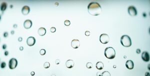 Detailed view of glistening water droplets on a transparent surface, perfect for abstract backgrounds.