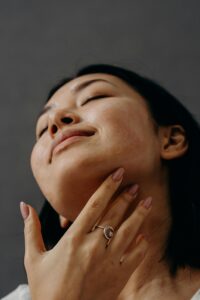 Woman enjoying a facial massage with closed eyes and relaxed expression, promoting self-care and wellness.