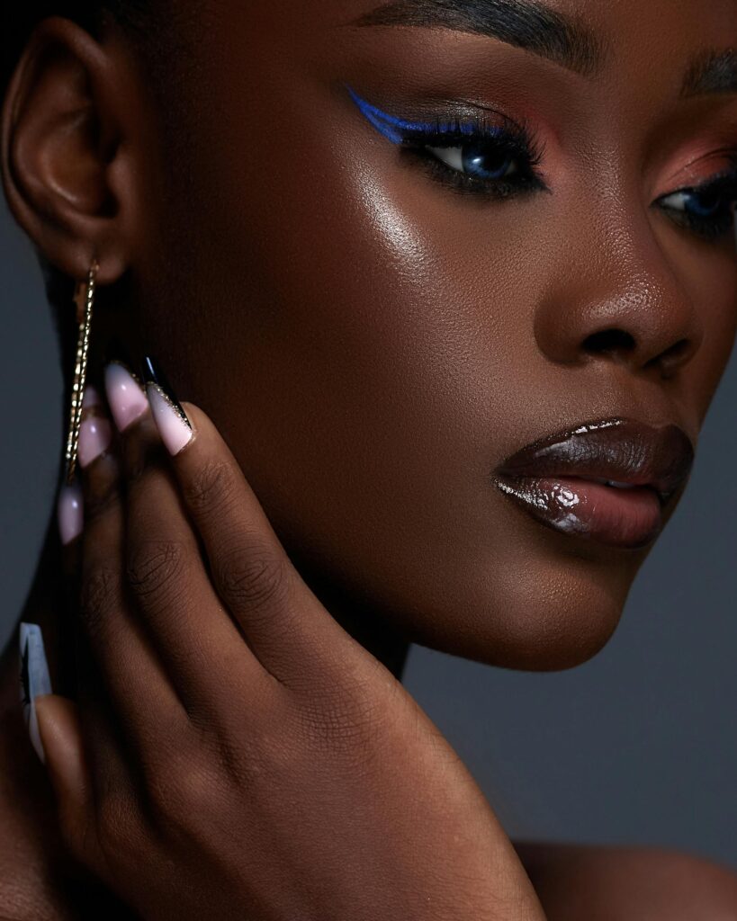 Vibrant close-up portrait of a woman with blue eyeshadow and manicured nails.