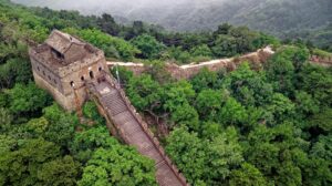 Drone shot of the Great Wall of China amidst lush greenery in Huairou, Beijing.