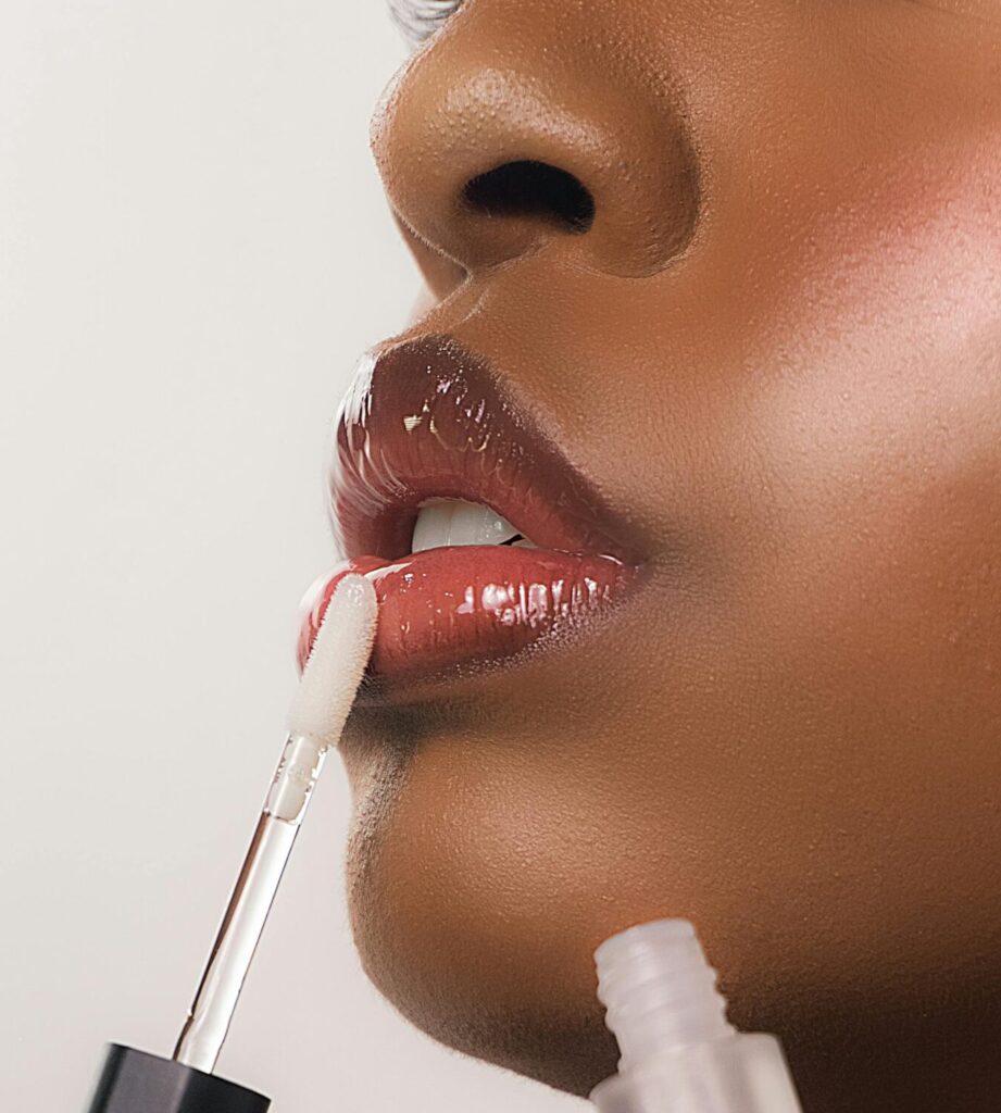 Detailed close-up of a black woman applying lip gloss, showcasing beauty and self-care.