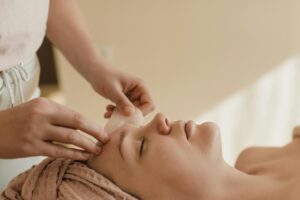 A calming side view of a woman receiving a gua sha facial massage indoors, promoting healthy skin.