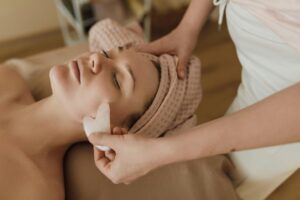 Woman receiving a calming facial massage using a gua sha tool in a spa setting.