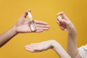 Hands using hand sanitizer against a yellow background, highlighting hygiene.